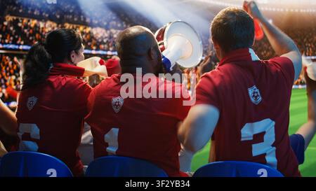 Nahaufnahme von fröhlichen Fußballfans, die sich auf Stadiontribünen tummeln, begeistert vom Tor in letzter Minute. Emotionale Fußballfans umarmen sich nach dem Sieg von der Lieblingsmannschaft Stockfoto