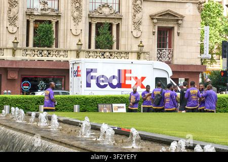 DALLAS, TX, USA - 11. JULI 2026: Ein FedEx-Lieferwagen ist vor einem prächtigen historischen Gebäude in Dallas, Texas, geparkt. Die Szene umfasst eine Gruppe Stockfoto