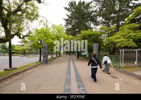Fußgänger gehen einen von Bäumen gesäumten Weg in Noboriōjichō, Nara, Japan entlang. Das Bild fängt eine alltägliche Szene des städtischen Lebens in der Kansai-Region ein Stockfoto