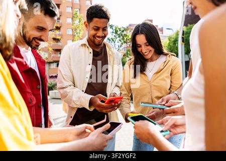Junge Gruppe von Menschen, die zusammen im Freien Mobiltelefone benutzen Stockfoto