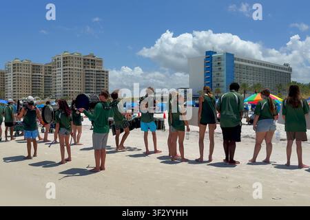 Eine Schüler-Marschkapelle in grünen Uniformen steht auf dem weißen Sand von Clearwater Beach, Florida, während einer Sommeraufführung. Stockfoto