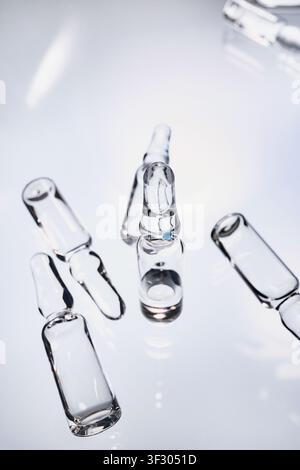 Sterile Glasampullen auf reflektierender Oberfläche, symbolisch für Forschung und Gesundheitswesen Stockfoto