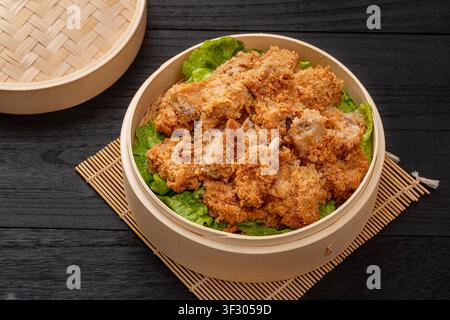 Chinesische gedämpfte Schweinerippchen mit gerösteter Reismehlfüllung in einem Bambusdampfer. Stockfoto