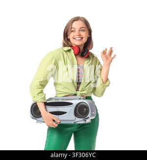 Lächelnde junge Frau mit roten Kopfhörern um den Hals, die eine Retro-Boombox hält, isoliert auf weißem Hintergrund, sie steht und macht eine Handgeste Stockfoto