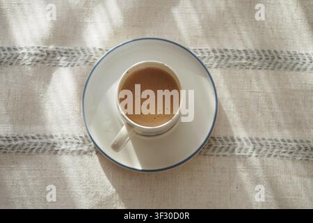 Warme Tasse Kaffee auf einem Tisch mit einem einfachen Tuch Stockfoto
