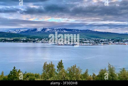 Die Panoramaansicht von Akureyri mit der Schneegebirgskette im Hintergrund zur goldenen Stunde, vom Meer aus, Nordisland Stockfoto