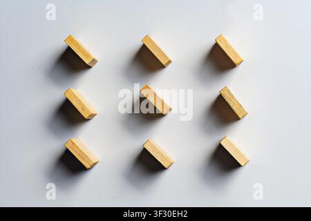 Hochwinkel-minimalistische Aufnahme von neun Holzblöcken, die ordentlich in einem 3x3-Raster auf einem weißen Hintergrund mit weichen Schatten angeordnet sind, was Ordnung und Struktur symbolisiert Stockfoto