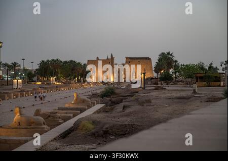 Eine panoramische Dämmerungsansicht des Tempels von Luxor in Luxor, Ägypten, mit dem alten Komplex, der von warmem künstlichem Licht gegen einen tiefblauen Abendhimmel beleuchtet wird Stockfoto