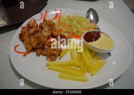 Nahaufnahme von knusprigem gebratenem Huhn, serviert mit Pommes, frischem Salat und cremigen Dipsaucen Stockfoto