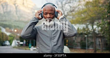 Fitness, Kopfhörer und Porträt eines schwarzen Mannes im Freien für den Beginn des Trainings oder der Trainingsroutine. Bewegung, Musik und ernst mit reifem Läufer in Stockfoto