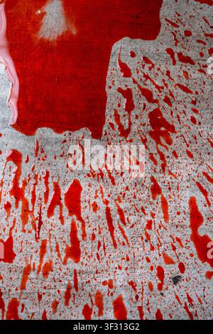 Intensive rote Blutspritzer und eine Pfütze auf einem strukturierten grauen Betonboden, die eine dramatische und spannungsgeladene Atmosphäre für Tatort oder Horror schaffen Stockfoto