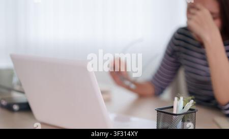 Junge asiatische Berufsfrau, die während einer Remote-Arbeitsitzung zu Hause Arbeitsstress und emotionalen Burnout erlebt Stockfoto