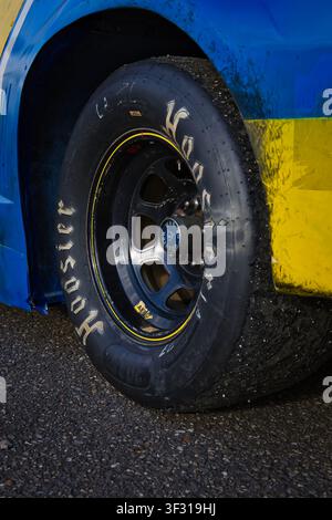 Nahaufnahme eines abgenutzten Hoosier-Rennschlauchreifens an einem Stock-Car in der Boxengasse, der nach dem Rennsport Gummiablagerungen zeigt. Stockfoto