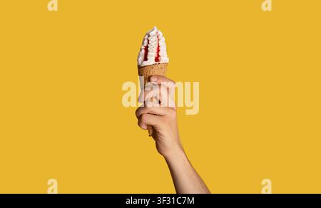 Millennial Kerl mit leckeren Eis mit Obst Topping in Waffel-Kegel, orange Hintergrund, Nahaufnahme. Panorama Stockfoto