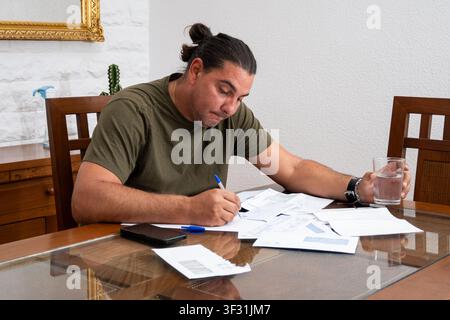 Mann, der zu Hause Finanzen berechnet und Rechnungen bezahlt, leidet unter finanzieller Belastung Stockfoto