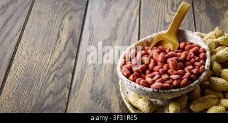 Erdnüsse in einer Schüssel mit Löffel auf Holzoberfläche mit Kopierraum. Stockfoto