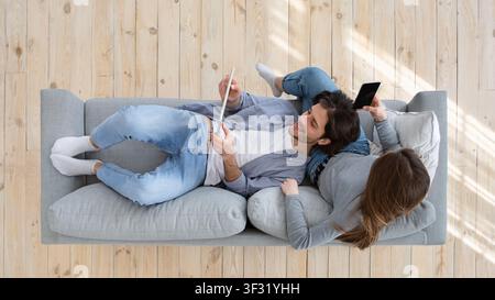 Draufsicht auf Familie auf Couch sitzen, mit Tablet, Telefon Stockfoto