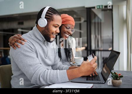 Glückliches schwarzes Paar beim Online-Shopping mit Kreditkarte und Laptop Stockfoto