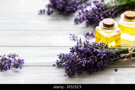 Frische Lavendelflumen und ätherische Öle in Flaschen auf einem weißen Holz-Hintergrund Stockfoto