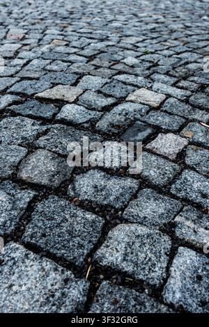 Niedriger Nahaufnahme einer alten unebenen Kopfsteinpflasterstraße, die verwitterte Steinblöcke, Textur und Perspektive zeigt Stockfoto