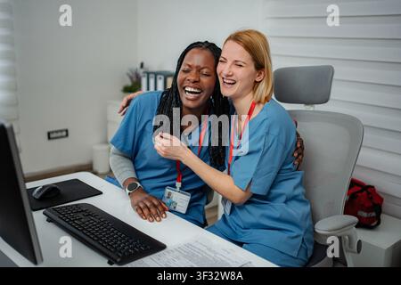 Diverse Mediziner lachen gemeinsam am Krankenhaustisch Stockfoto