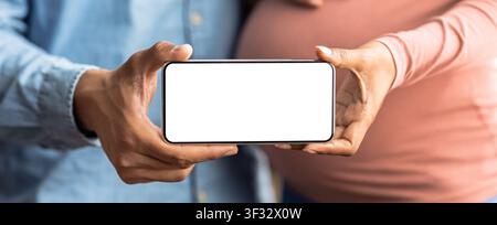 Paar hält Smartphone mit leerem Bildschirm, erwartet ein Baby, Schwangerschaftskonzept Stockfoto