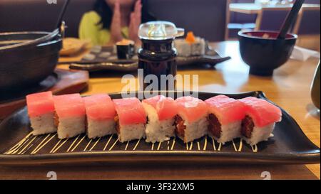 Scharfer Maguro-Roll-Sushi, serviert auf einem schwarzen Teller in einem japanischen Restaurant, mit frischem Thunfisch, der mit Sushi-Reis und Nori gewickelt ist. Stockfoto