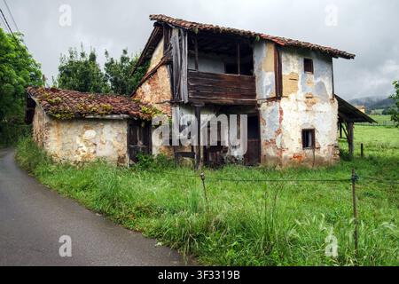 Altes, verlassenes, verfallenes traditionelles Bauernhaus neben einer Landstraße auf dem Camino Primitivo in Asturien, Spanien. Stockfoto