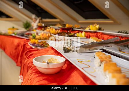 Breite Auswahl an Sushi, Maki-Rollen und anderen Gerichten, bereit für die Gäste an einem Restaurant-Buffet Stockfoto