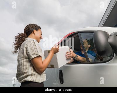 Frau, die ein Paket von einem Lieferwagenfahrer entgegennimmt Stockfoto