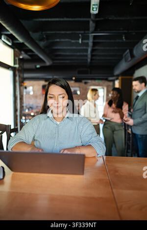Junge erwachsene Frau arbeitet an einem Laptop in einem modernen Café Stockfoto