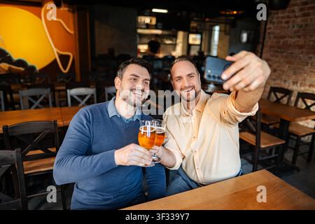 Zwei Erwachsene Männer, die Bier trinken und Selfie in der Bar machen Stockfoto