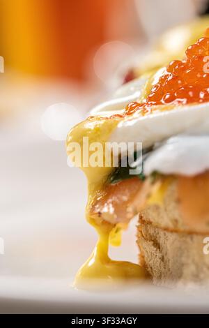Nahaufnahme von Eggs Benedict mit Lachsrogen und schmelzender Hollandaise Stockfoto