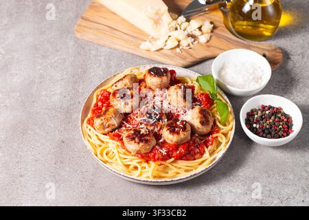 Ein Teller mit klassischen Spaghetti, garniert mit gebräunten Fleischbällchen und reichhaltiger Tomatensauce auf einem leichten Keramikgericht. Stockfoto