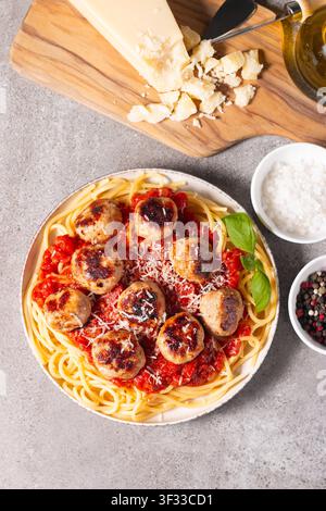 Ein Teller mit klassischen Spaghetti, garniert mit gebräunten Fleischbällchen und reichhaltiger Tomatensauce auf einem leichten Keramikgericht. Stockfoto