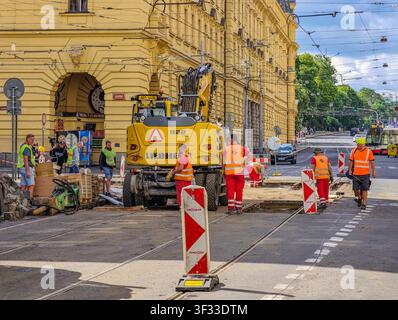 Prag, Tschechische Republik - 21. Juli 2026: Bauarbeiter reparieren Straßenbahnschienen und die umliegende Fahrbahn im Stadtzentrum mit schweren Maschinen Stockfoto