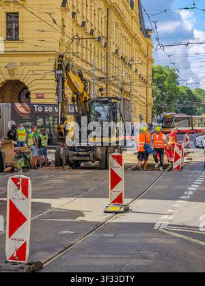 Prag, Tschechische Republik - 21. Juli 2026: Bauarbeiter reparieren Straßenbahnschienen und die umliegende Fahrbahn im Stadtzentrum mit schweren Maschinen Stockfoto