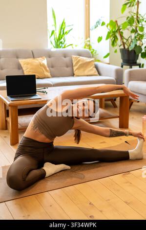 Lächelnde junge Frau macht seitliche Beugung Dehnung Stockfoto