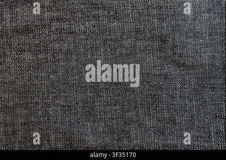 Makro-Vollbilddetail von dunkelgrauem oder schwarzem Denimtextil, das ein diagonales Twill-Gewebe Muster zeigt. Hochwertiges nahtloses Stil-Hintergrundkonzept für Mode, Bekleidung Design, Freizeitkleidung oder Hintergrundtapete. Stockfoto