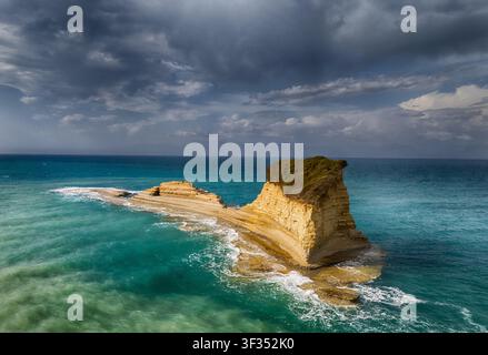 Luftaufnahme von Cape Drastis mit dramatischen Kalksteinklippen und türkisfarbenem Wasser unter einem stürmischen Himmel in Korfu, Griechenland. Stockfoto