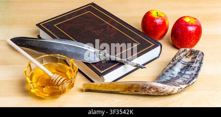 Jüdische Neujahrs-Symbole, darunter Schofar, Honig, Äpfel, Buch und Feder auf Holzoberfläche Stockfoto