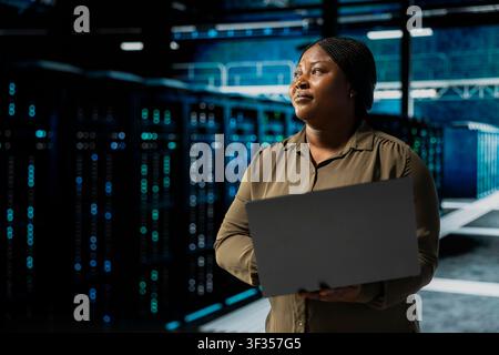 Admin verwendet Laptop zur Wartung von Rechenzentrumselektronik, die große Datensätze verarbeitet. Serverfarm-Mitarbeiter führt Backups auf dem Notebook durch, um die Infrastruktur zu schützen, die von Cloud-Speicher-Hostingunternehmen genutzt wird Stockfoto