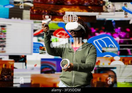 Junge Frau nutzt VR-Headset-Ausrüstung, um Freizeit mit Inhalten auf Video-Streaming-Diensten zu genießen. Person schaut VOD-Sendung mit Virtual-Reality-Technologie vor digitalem Hintergrund Stockfoto