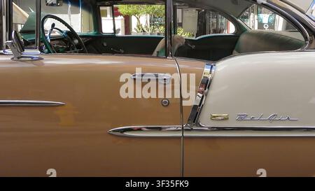 Eine Nahaufnahme von der Seite eines klassischen Autos, ein Vintage-1955-Chevrolet-Bel-Air. Die Aufnahme betont die zweitonige Körperlackierung in Beige und Creme sowie die Chromdo Stockfoto