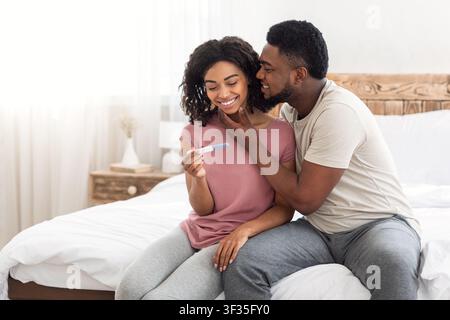 Liebevoller schwarzer Mann küsst seine schwangere Frau oder Freundin Stockfoto