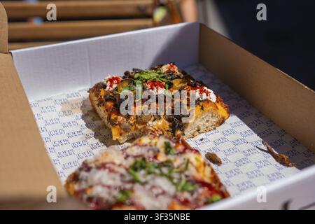 Zwei Pizzascheiben mit verschiedenen Belägen in einer Pizzaschachtel im Sonnenlicht, Dublin, Irland Stockfoto