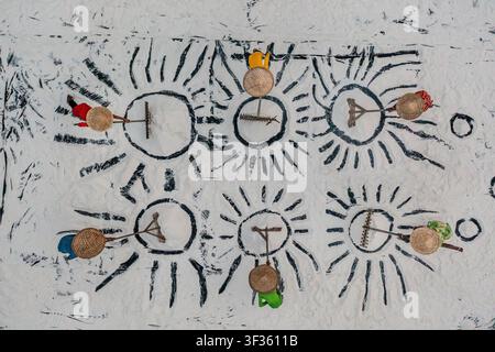 Midnapore, West Bengal, Indien – 15. November 2024: Luftbild von Salzarbeitern, die Kegelhüte tragen und Salz in sonnenartigen Mustern auf einer weiten weißen Fläche zusammenkehren Stockfoto