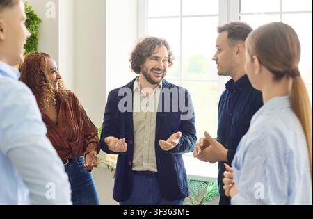 Junge Freunde, die bei einem lockeren Treffen zu Hause drinnen plaudern, fröhliches Gespräch Stockfoto