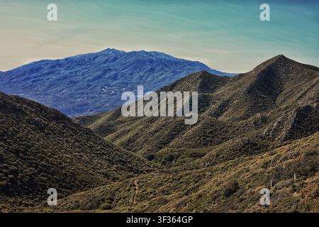 Schichtartige Bergkämme mit Blick auf einen blauen fernen Gipfel Stockfoto
