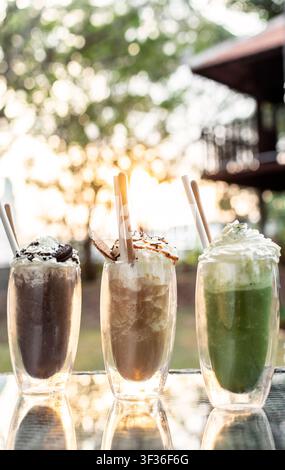 Schokoladen-, Kaffee- und Matcha-Eis-Sundae-Milchshake-Getränke auf einem Außentisch eines Cafés im Sommer Stockfoto